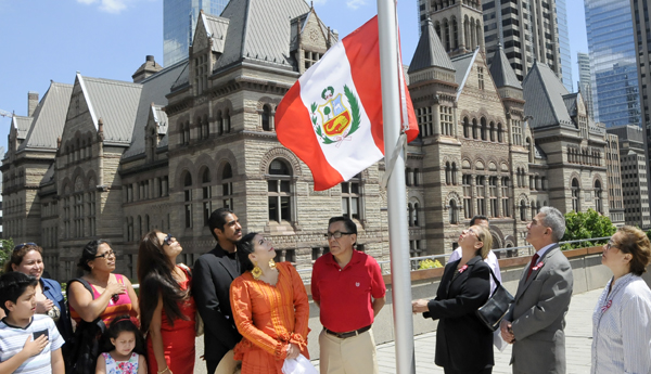 La Cónsul General del Perú en Toronto, Mary Ann Silva de Espinosa, iza la bandera peruana al ritmo de la “Marcha de Banderas”. 