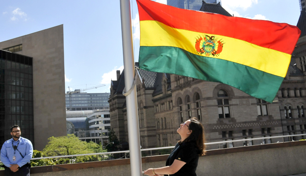 La encargada de la Embajada de Bolivia en Canadá, Claudia Rocabado, iza la bandera boliviana en la municipalidad de Toronto.
